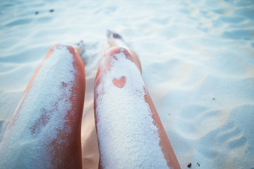 Female feet on the white sand beach in shallow water