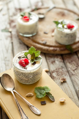 Chia seed pudding with raspberries chocolate and mint in jars. Vertical shooting.