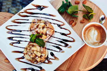 pancakes with chocolate and fruit and coffee on wooden background. Beautiful restaurant serving the dessert