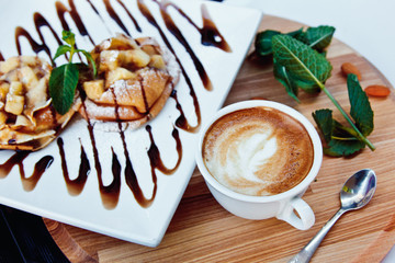 pancakes with chocolate and fruit and coffee on wooden background. Beautiful restaurant serving the dessert