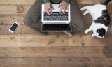 Woman sitting on a wooden floor using her laptop.