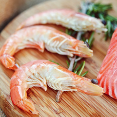 Raw salmon and shrimps with rosemary and lemon on the wooden board