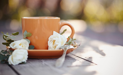 Orange cup with a spoon and a white dogrose