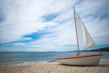 Sail boat on tropical beach with blue water background