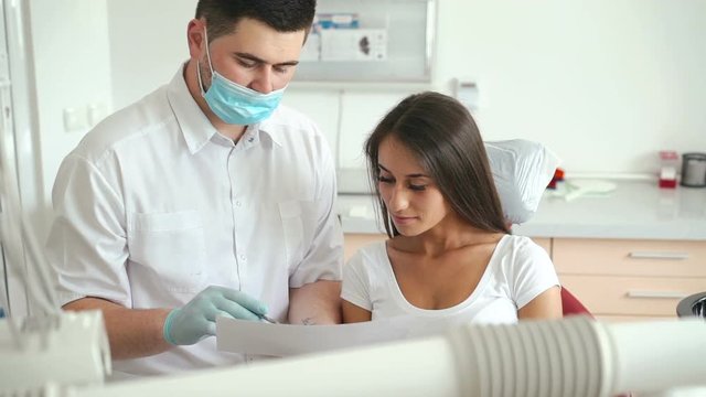 Dentist explaining procedure to female patient in dentist room