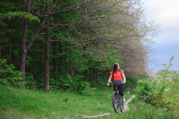 Fototapeta premium Girl riding a bike in the woods