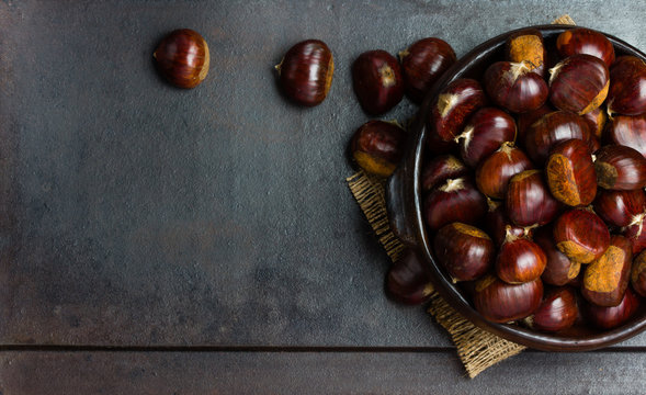 Chestnuts castanas in clay bowl on black background
