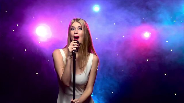 Girl singing into retro microphone with smoke effect. Slow motion