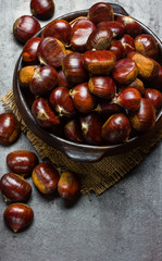 Chestnuts castanas in clay bowl on black background