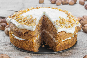 Cut Carrot and Walnut Cake Topped with Cream  on Jute Background