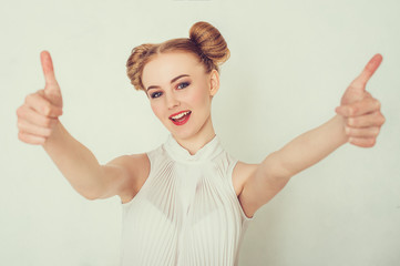 Beautiful young woman in casual clothes is showing Ok sing, looking at camera.