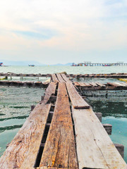 A wooden fishing bridge floating on the sea in Phuket , Thailand, with partly cloud sky and pier as a background.