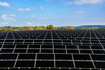 A field of solar cell placing with the scenery on trees and mountain.