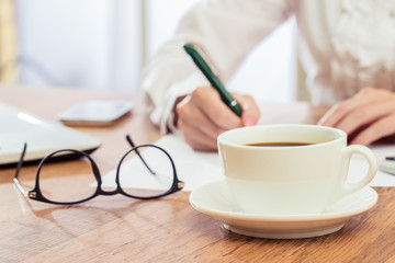 Businesswoman writing and drink coffee at desk