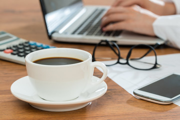 Businesswoman using laptop and drink coffee at desk