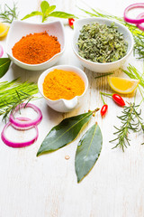 Dry colorful spices in bowls with fresh seasoning on white