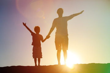 silhouettes of father and son having fun at sunset