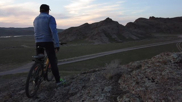 cyclist riding out to the pass admires sunset
