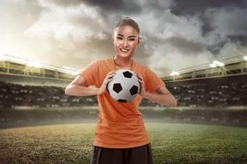Fototapeten Happy female football fan holding ball © Leo Lintang