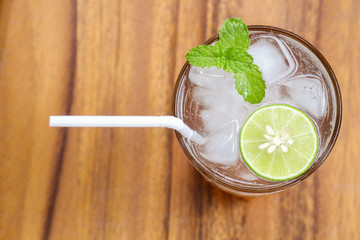 Top view of fresh cocktail with lime slice and mint on wood back