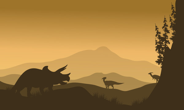 Parasaurolophus and Triceratops in hills of silhouette