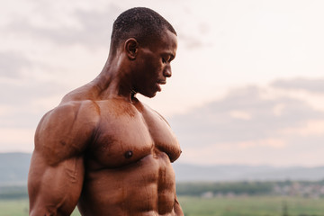 Portrait of handsome black african american bodybuilder on the sunrise sky background