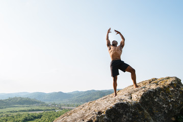 Emotional shot of black african american athlete man on the rock in mountains. Beauty and...