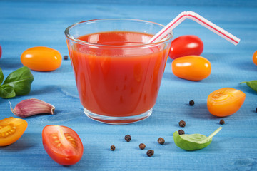 Tomato juice and vegetables with spices on blue board, healthy nutrition