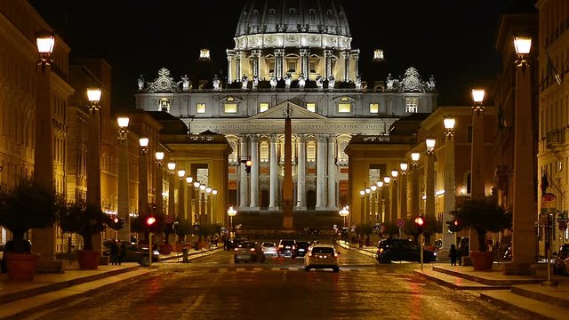 Night view of the Papal Basilica of Saint Peter in the Vatican (Basilica Papale di San Pietro in Vaticano). Vehicles passing across Via della Conciliazione.
