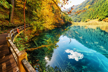 Wooden boardwalk leading along amazing lake with azure water