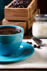 Cup of coffee and wooden containers filled with cofee beans