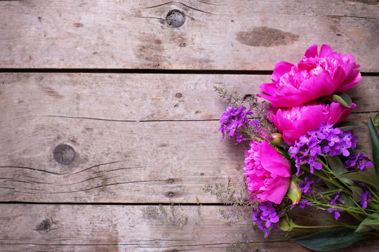 Pink peonies flowers on aged wooden background.