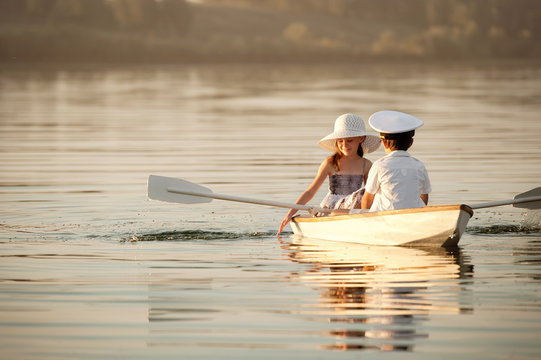 Boy with a girl floating on a boat rowed across the lake
