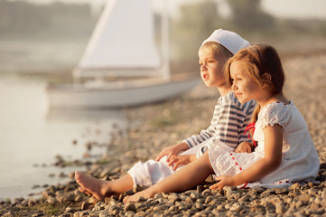 Boy and girl sitting on the bank of the lake and watch the sunset