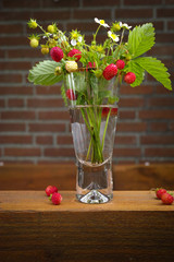 Clear glass vase with bunch of ripe red wild strawberries