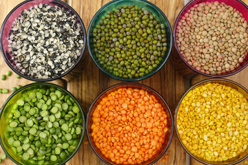 Multicolored clear glasses with various legumes ( green peas, re