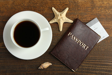 passport with a Cup of strong coffee on a brown wooden background with different shaped shells