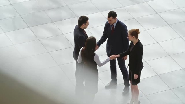 High angle view of business partners meeting in lobby of business center, shaking hands and talking, shot on Sony NEX 700