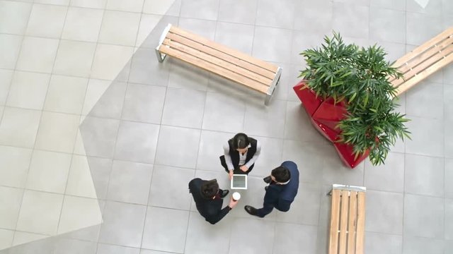 Group of business people in formalwear discussing business issues in lobby of office building, directly above view, tracking shot on Sony NEX 700