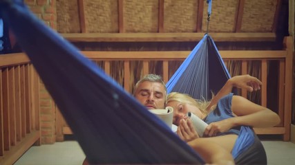 couple lying together on hammock reading relaxing at night before go to sleep - Powered by Adobe