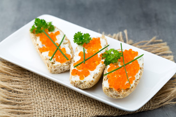 Red caviar on bread on white plate.