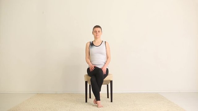 Young woman practicing yoga on chair. 