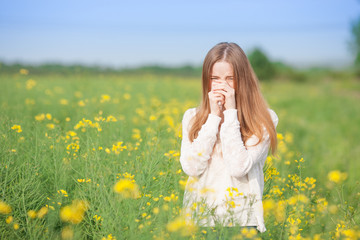 Pollen allergy, girl sneezing in a field of flowers.
