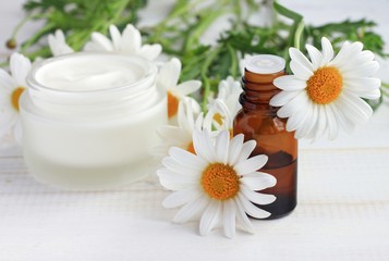 Fototapeta na wymiar Body cream white essential oil, chamomile daisy flowers. Herbal cosmetic products. Soft focus.