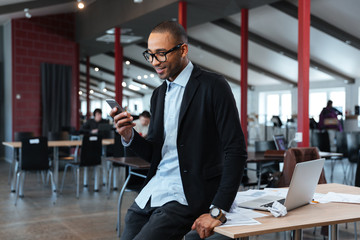 Smiling businessman texting message on the smartphone