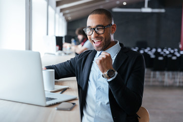 Handsome young businessman celebrating success with arms raised