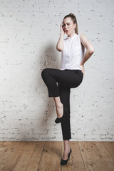 fashion model in black trousers and white blouse posing over whi