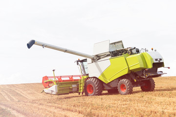 Obraz premium Modern combine harvester on stubble field at end of summer
