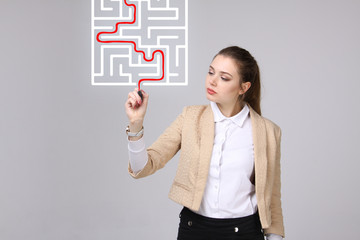 Young woman finding the maze solution, writing on whiteboard.