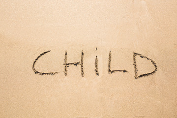 written word CHILD on sand of beach